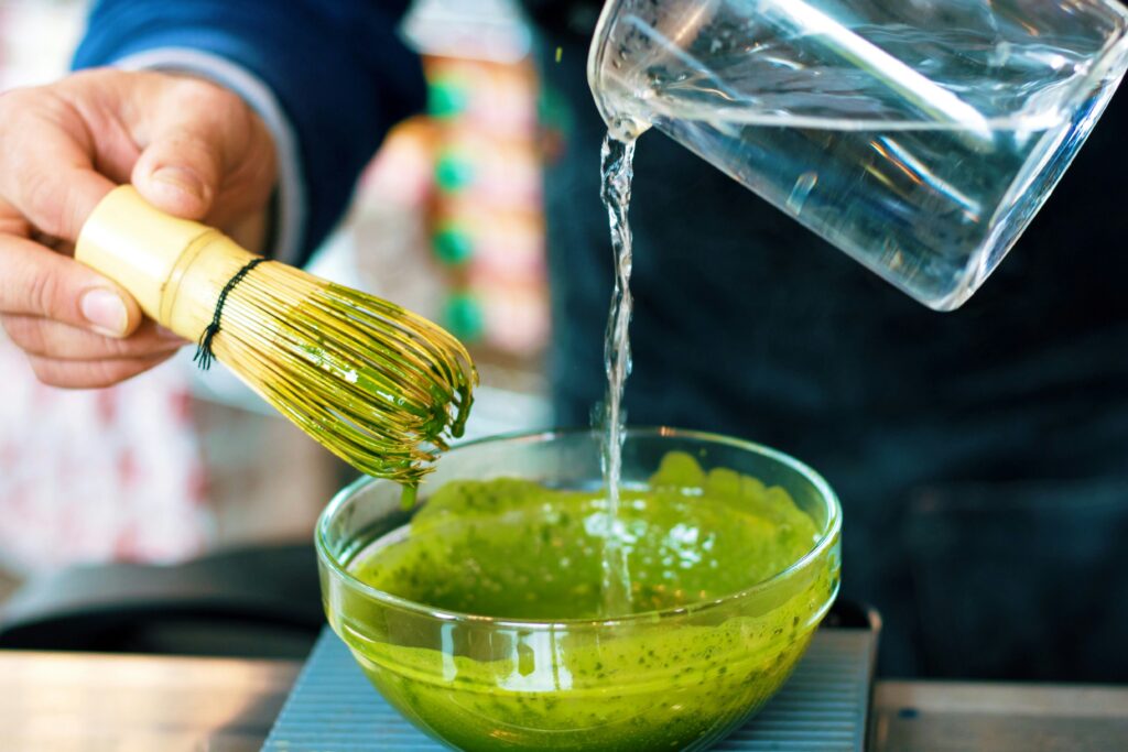 A close-up image of a person preparing matcha tea