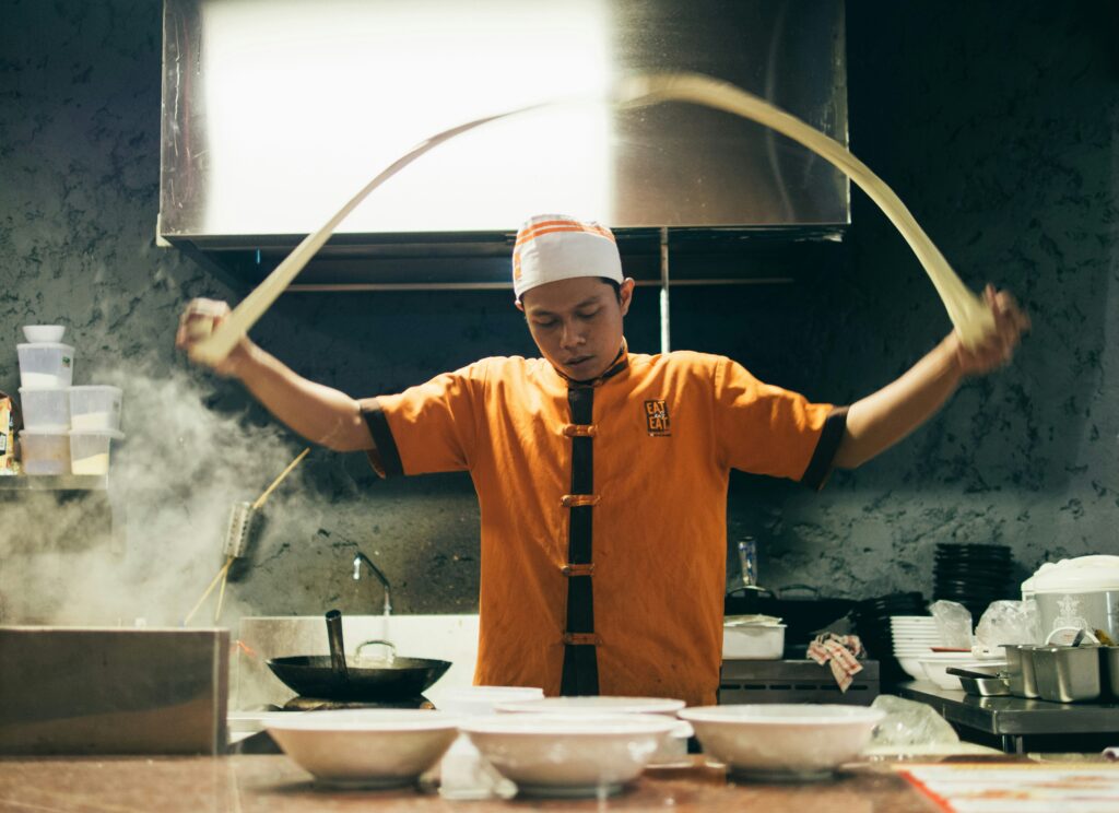 A cook by making ramen noodles in the kitchen