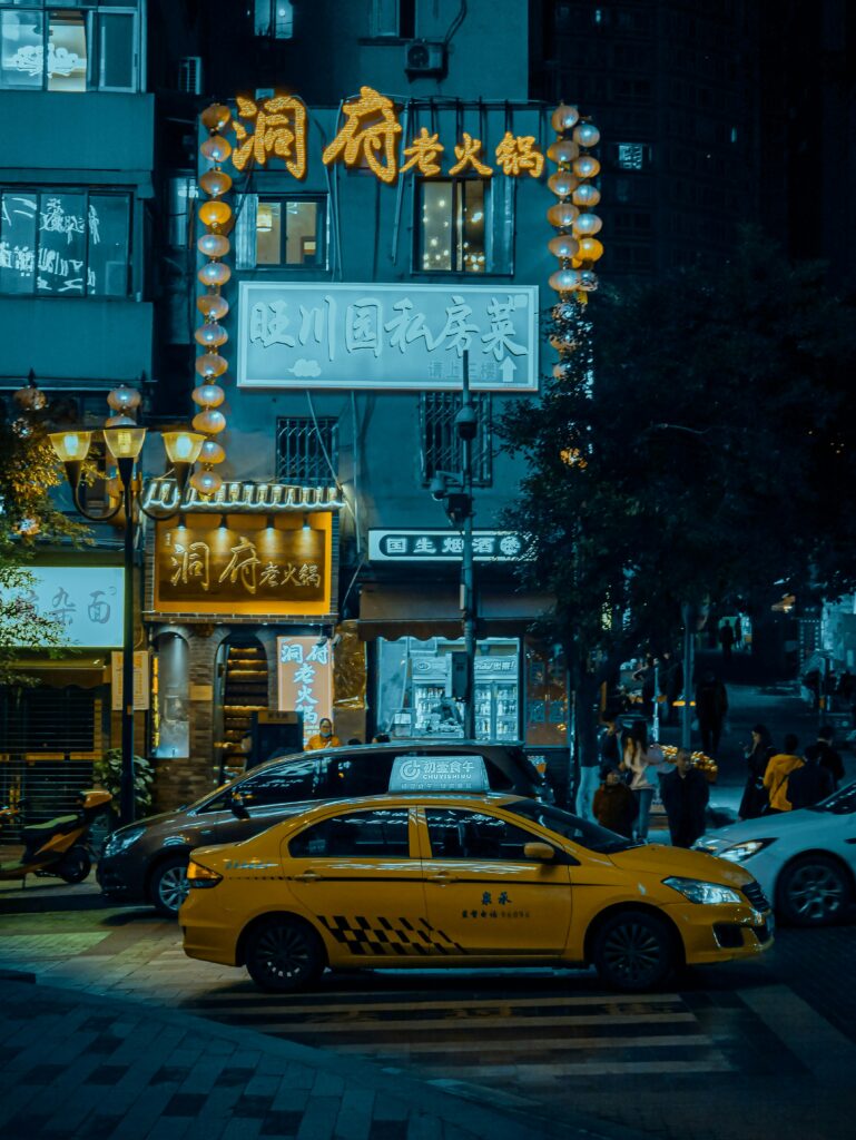 Yellow taxi car in front of a building by night somewhere in Chongqing