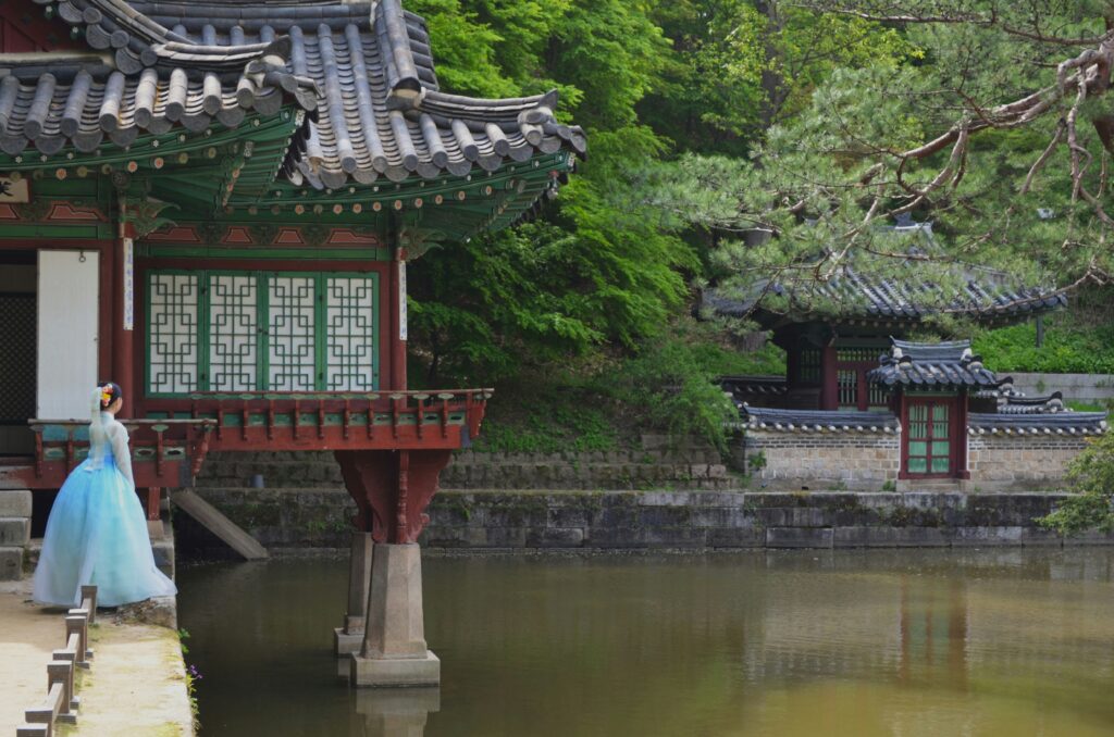 A serene scene in a traditional Korean palace or garden, featuring an elegant wooden pavilion with green 