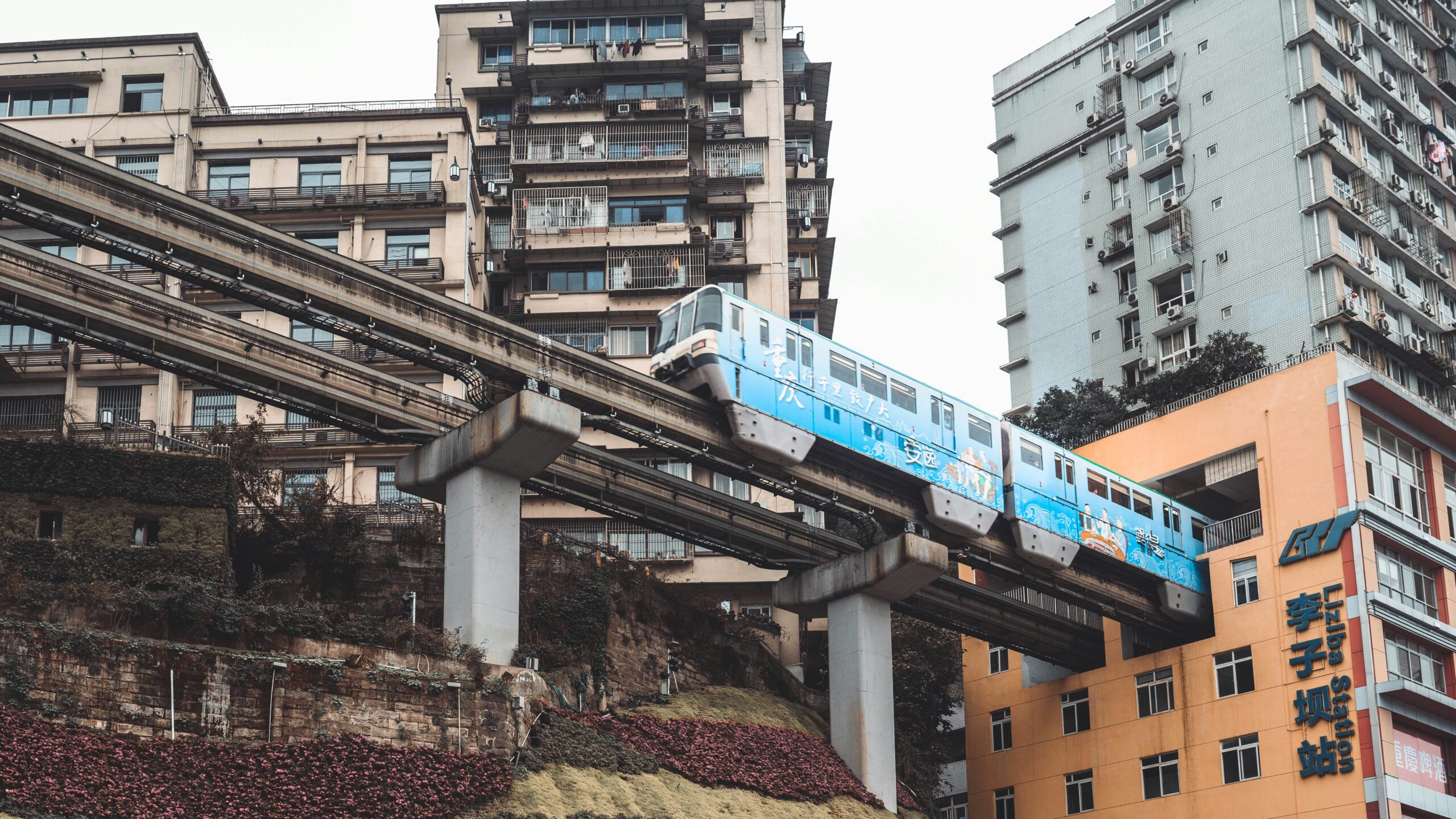 A unique urban scene featuring a blue monorail train emerging from the Liziba Station