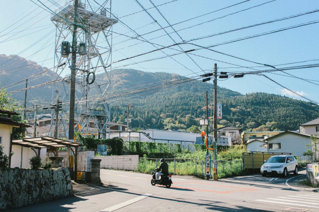 View of a road intersection with a motorcyclist and several aerial cables on masts