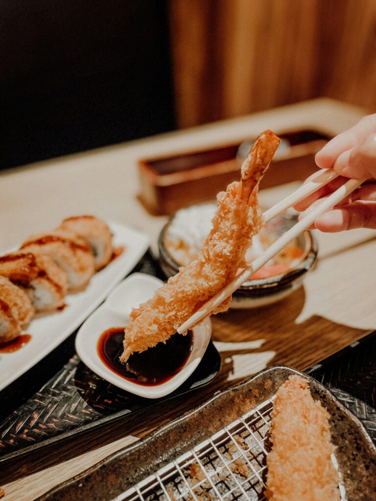 Tempura between two chopsticks over a plate
