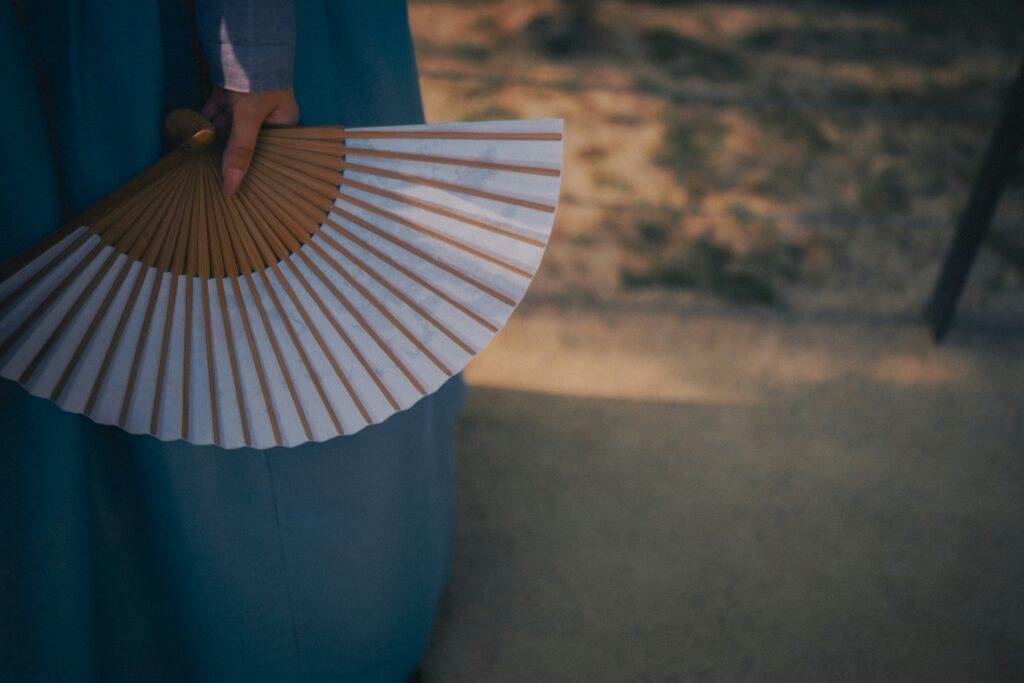 Close-up of a hand holding a folded fan
