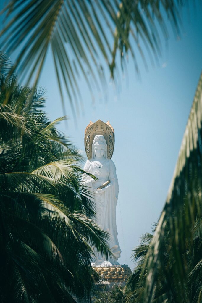 A statue in the distance and some palm branches in front